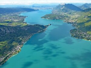 Vue aérienne spectaculaire montrant l'étendue du lac et des montagnes, terrain de jeu idéal pour toute activité Annecy en plein air.